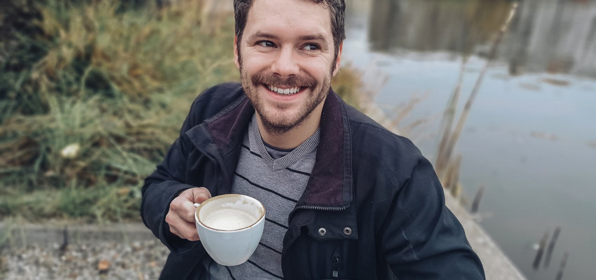 コーヒーカップ片手に笑顔の男性